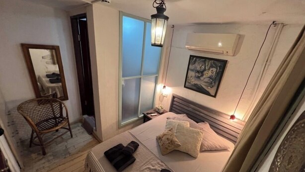 Quarto com cama, uma cadeira, janela e ar condicionado.