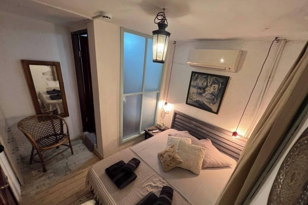 Une chambre à coucher avec un lit, une chaise, une fenêtre et un appareil de climatisation.