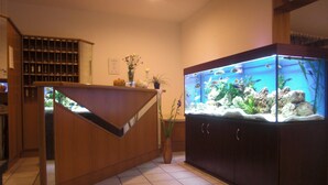 A reception area with a fish tank, tiled floor, and a staircase. - Hotel Evabrunnen (Bischofswerda)