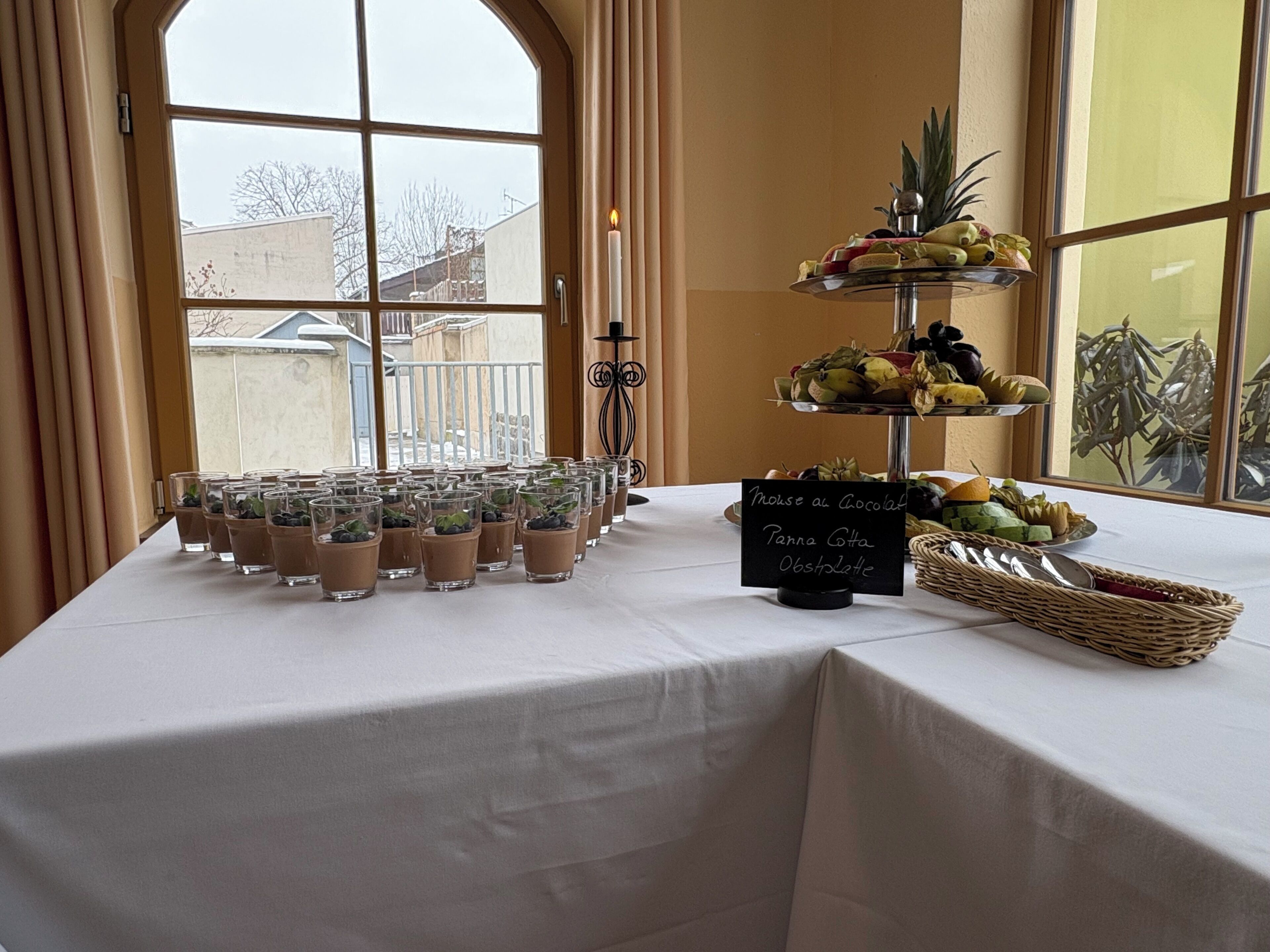 A table with chocolate mousse cups, a fruit display, and a sign indicating a chocolate dessert.