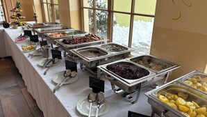 A buffet setup with various food items and utensils. - Hotel Evabrunnen (Bischofswerda)