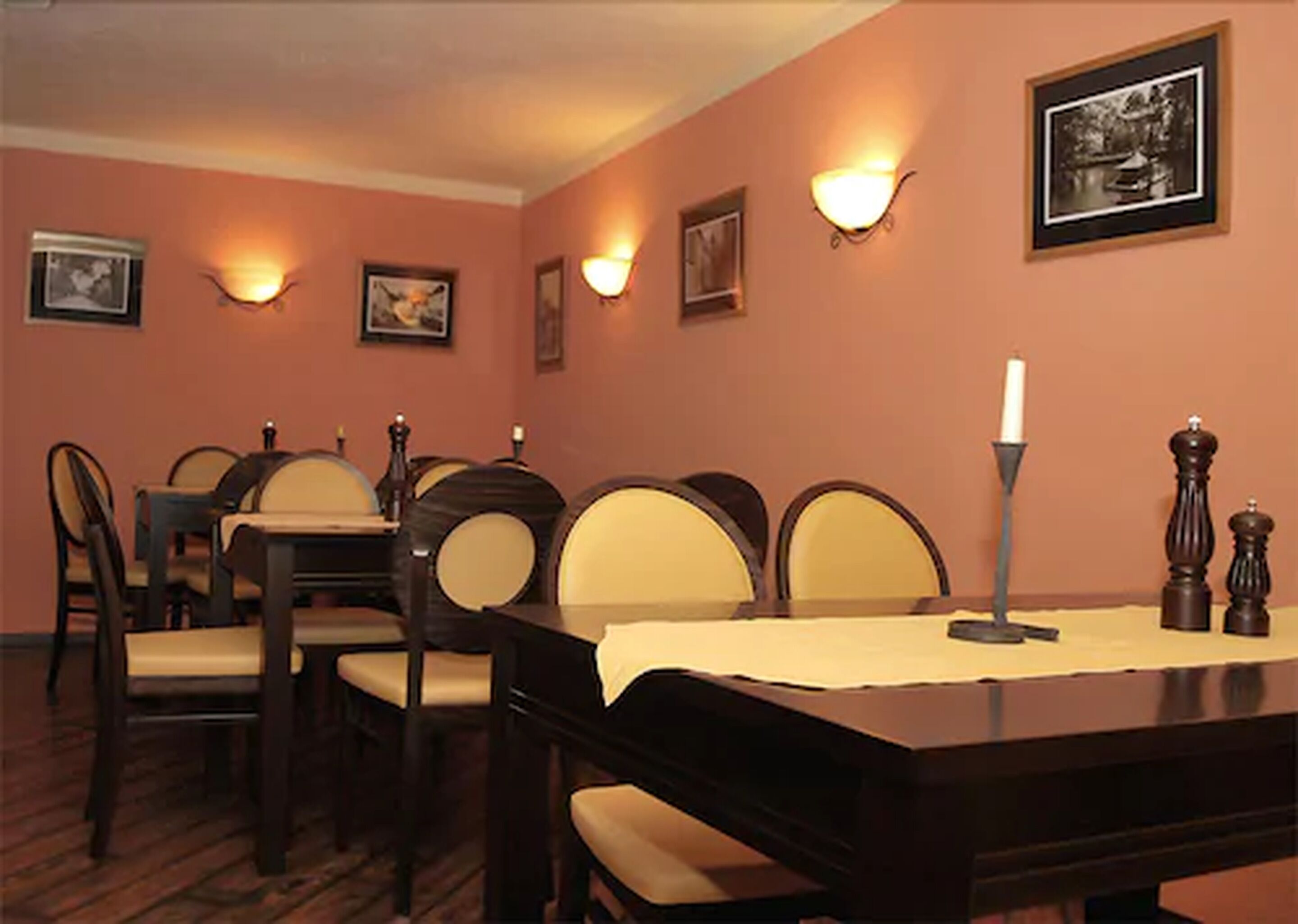 Un espace repas comprenant une table en bois, des chaises et des luminaires fixés au mur.