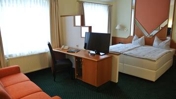 A hotel room with a desk, a television, a bed, and a chair.