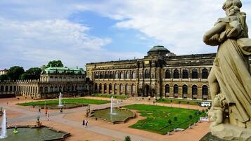 A grand building with a large courtyard, fountains, and a statue.