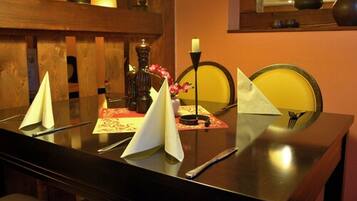 Una mesa de comedor dispuesta con servilletas blancas, una vela y un florero con flores.