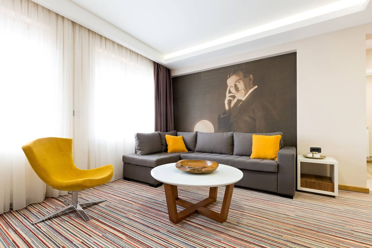 A modern living room with a yellow armchair, grey sofa, and a round coffee table.