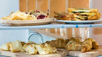 A breakfast buffet with pastries, sandwiches, and croissants.