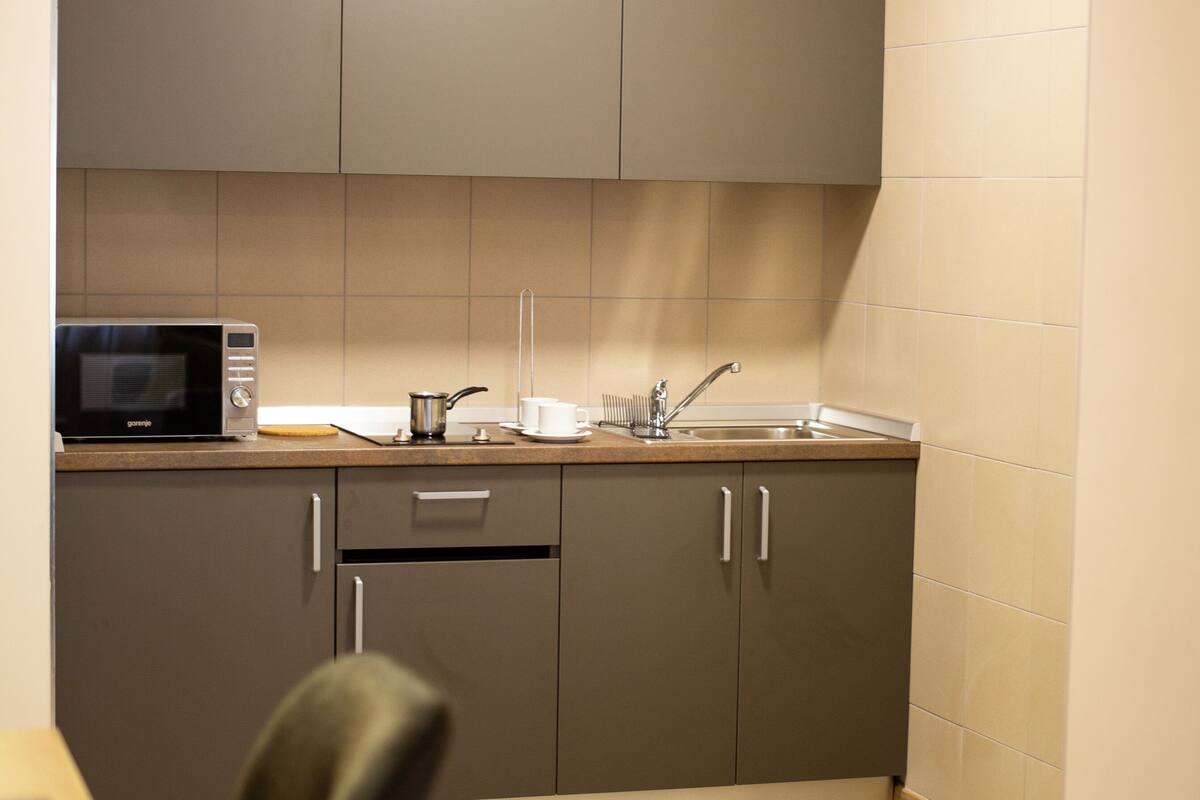 A compact kitchen with a microwave, sink, and cabinets.