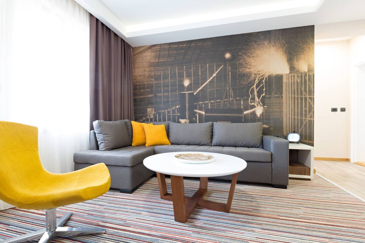 A modern living room with a sofa, a yellow chair, and a round coffee table.