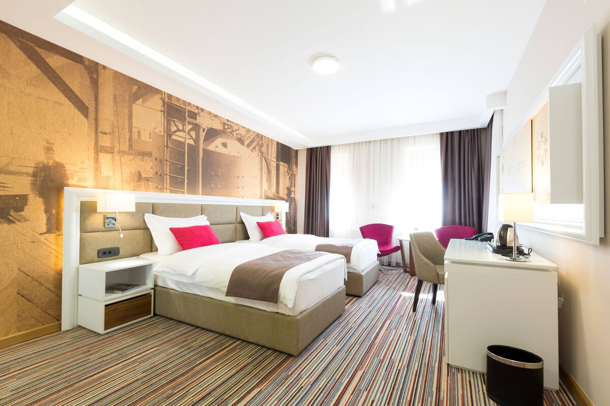 A hotel room with a large bed, two bedside tables, a desk, and a chair.