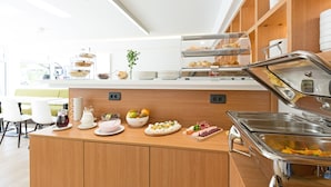 A buffet area with various food items, a coffee station, and a seating area with tables and chairs. - Hotel Tesla - Smart Stay (Belgrade)