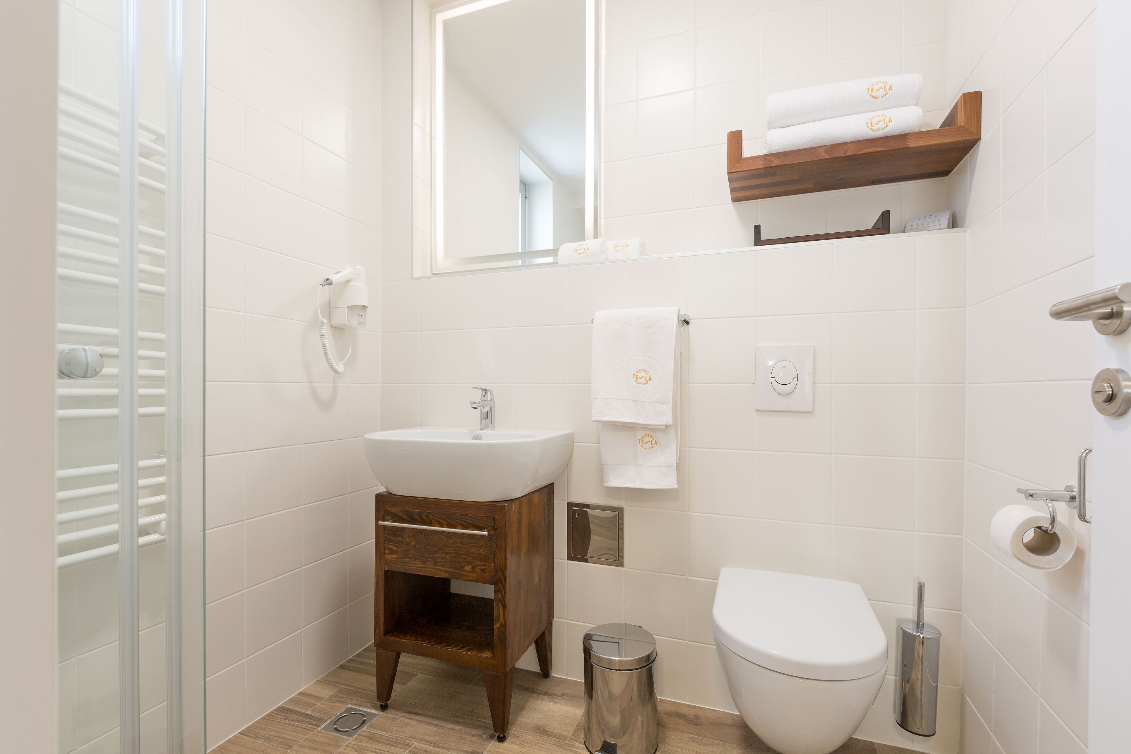 Un baño moderno con lavamanos, tocador, espejo, toallero, inodoro y un cubo de basura.