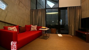 A modern living room with a red sofa, a small table with fruits, and a TV. - Smoking Rock Resort (Jiaoxi)