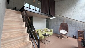 A modern interior with a staircase, a green sofa, a hanging chair, and a minimalist design. - Smoking Rock Resort (Jiaoxi)