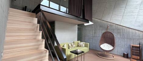Ein modernes Interieur mit Treppe, einem grünen Sofa, einem Hängesessel und minimalistischem Design.