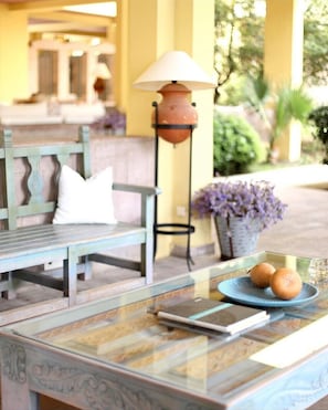 A glass-top table with a blue plate, a lamp, and a bench with a cushion. - Palm Court Suites (Ayvalik)