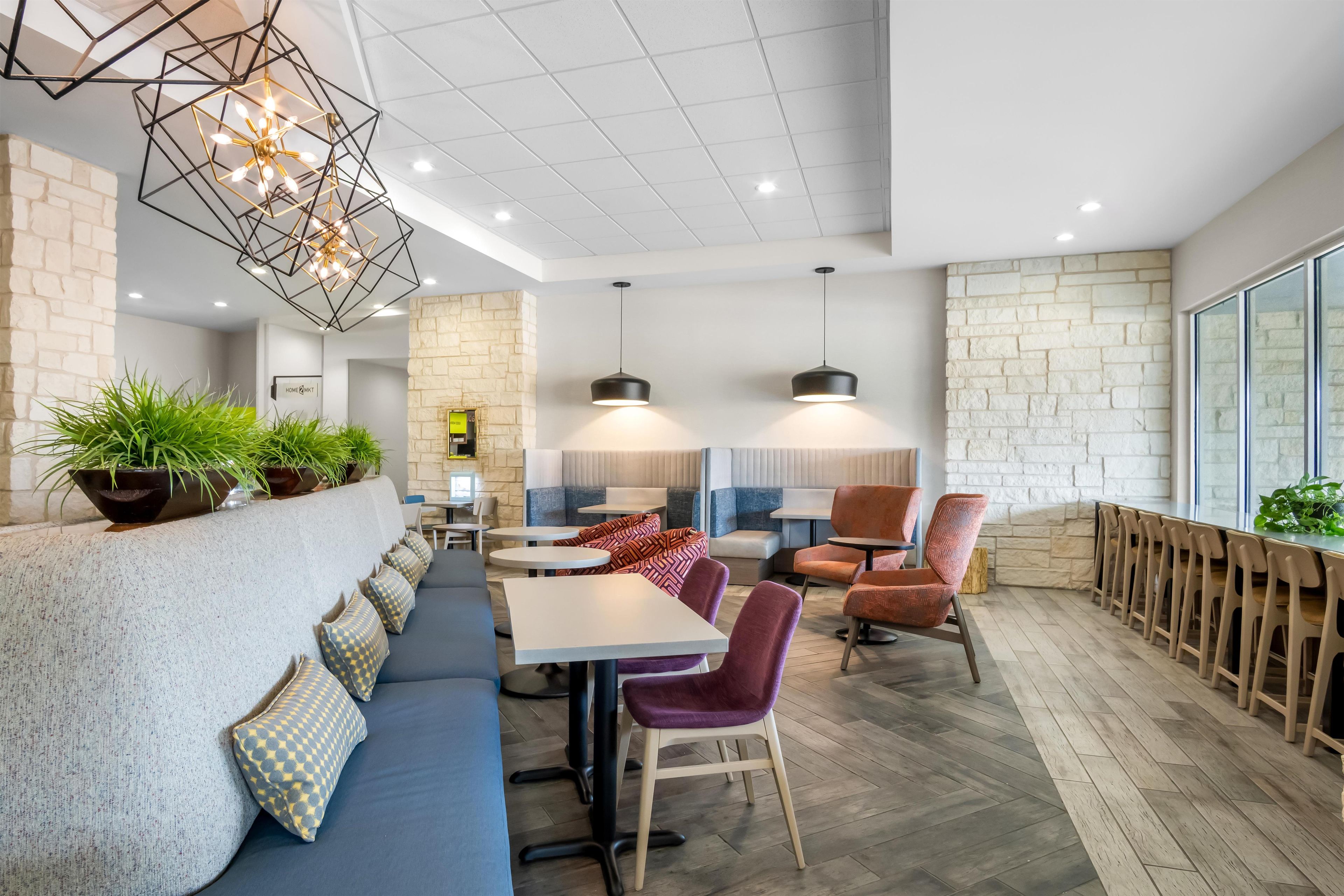A modern restaurant interior with a long counter, seating area, and decorative lighting.