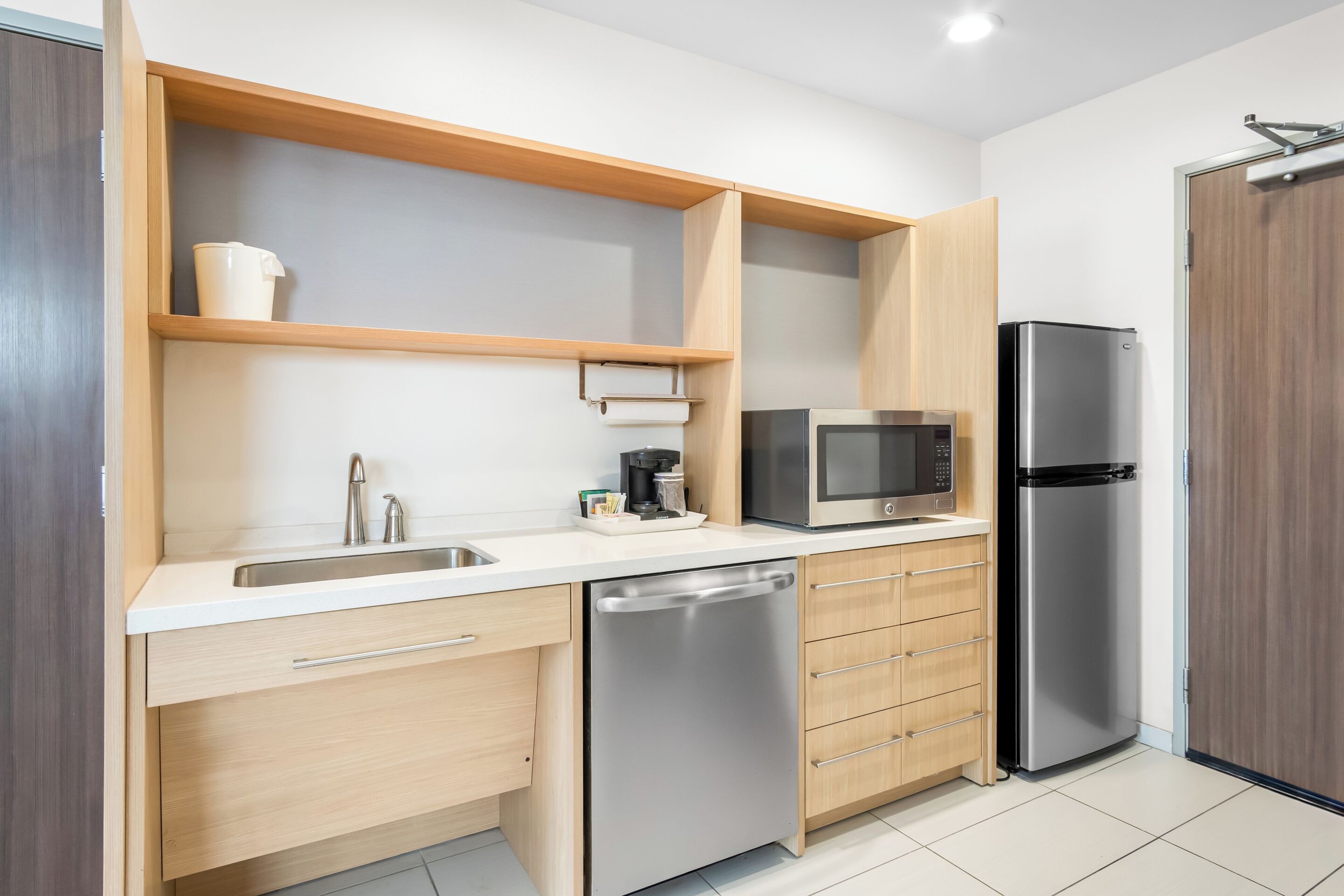 A modern kitchen with a stainless steel dishwasher, a microwave, and a refrigerator.