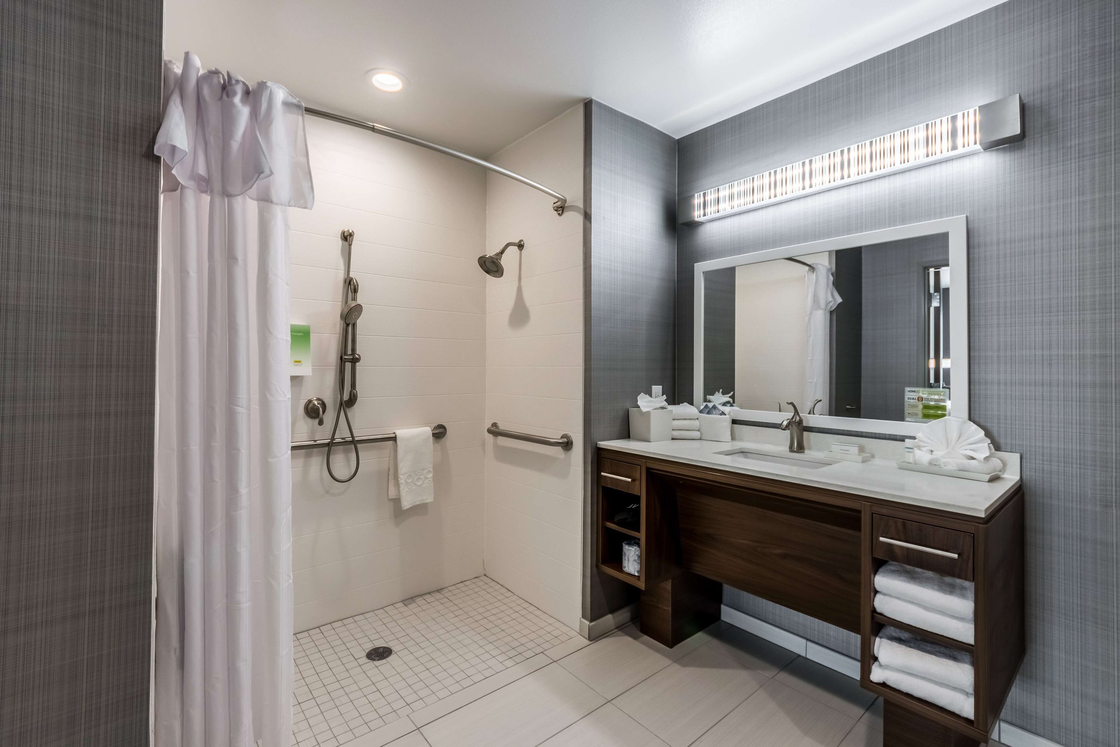 Een moderne badkamer met een inloopdouche, een wastafel met spiegel en een handdoekrek.