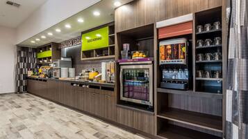Una barra de desayuno moderna con diversas opciones de comida y bebida, que incluye una estación de yogur y leche, y una máquina de café.