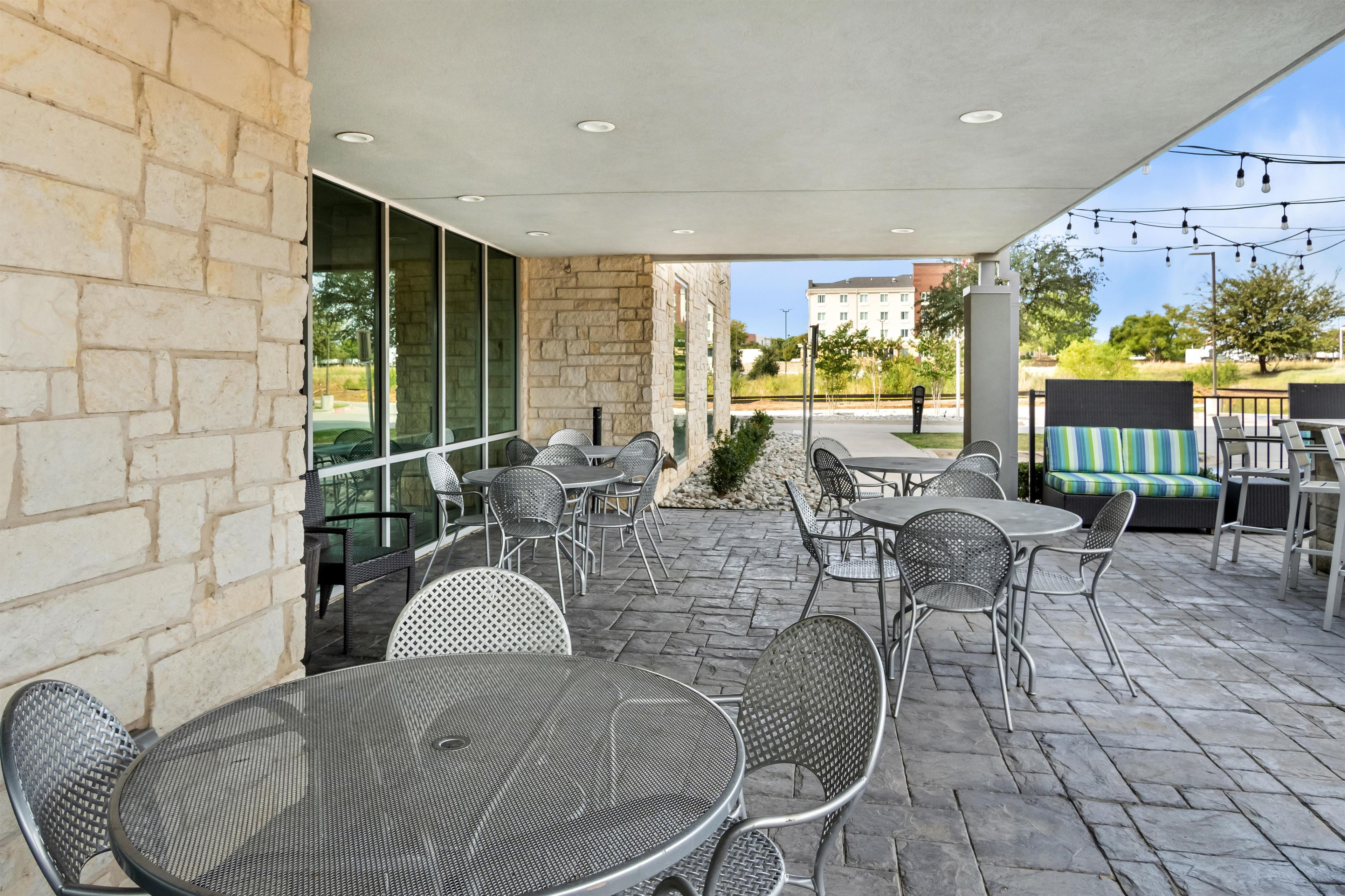 An outdoor patio area with stone flooring, metal chairs, and tables.