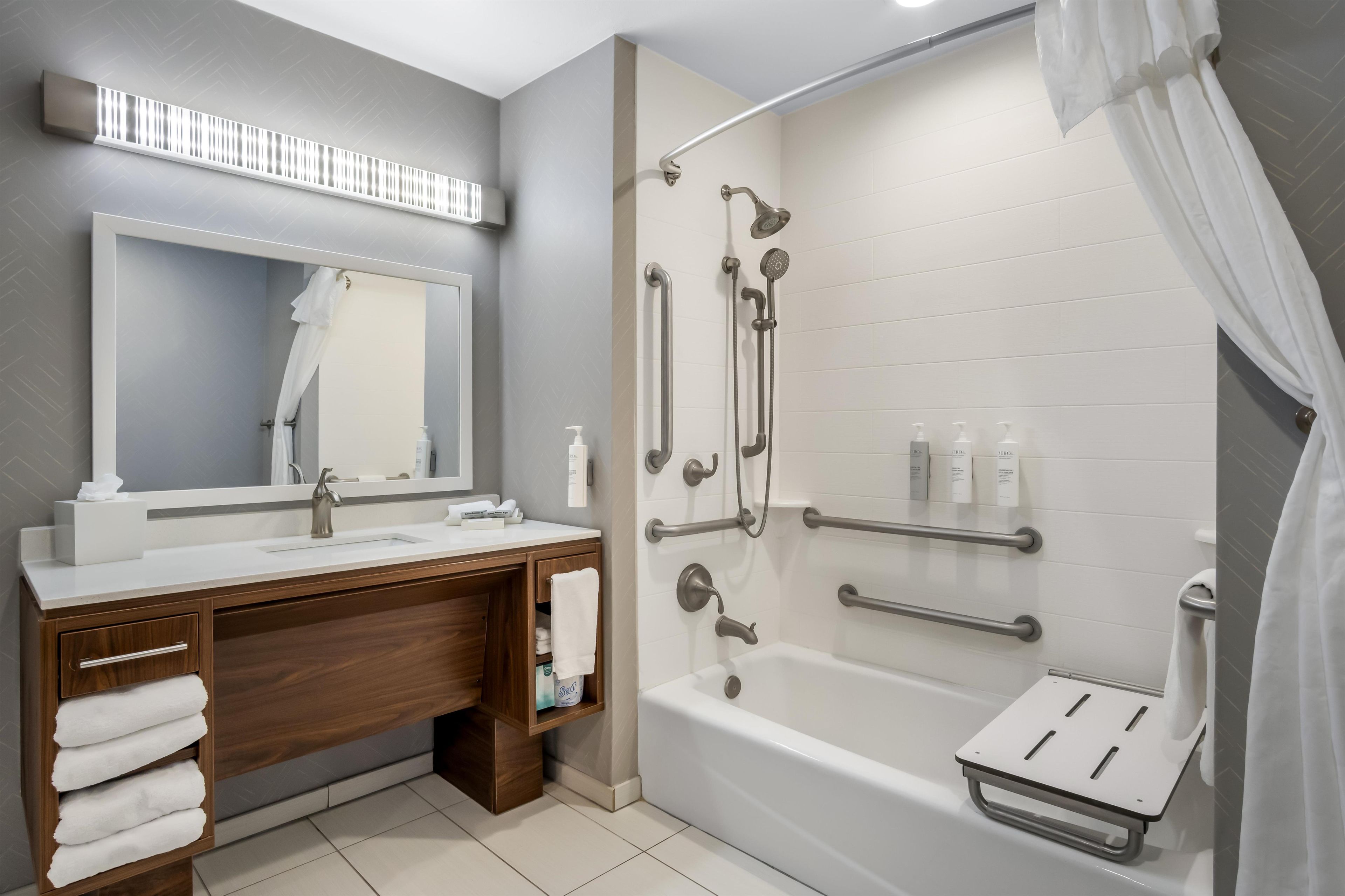 A modern bathroom with a shower, a vanity with a mirror, and a bathtub.