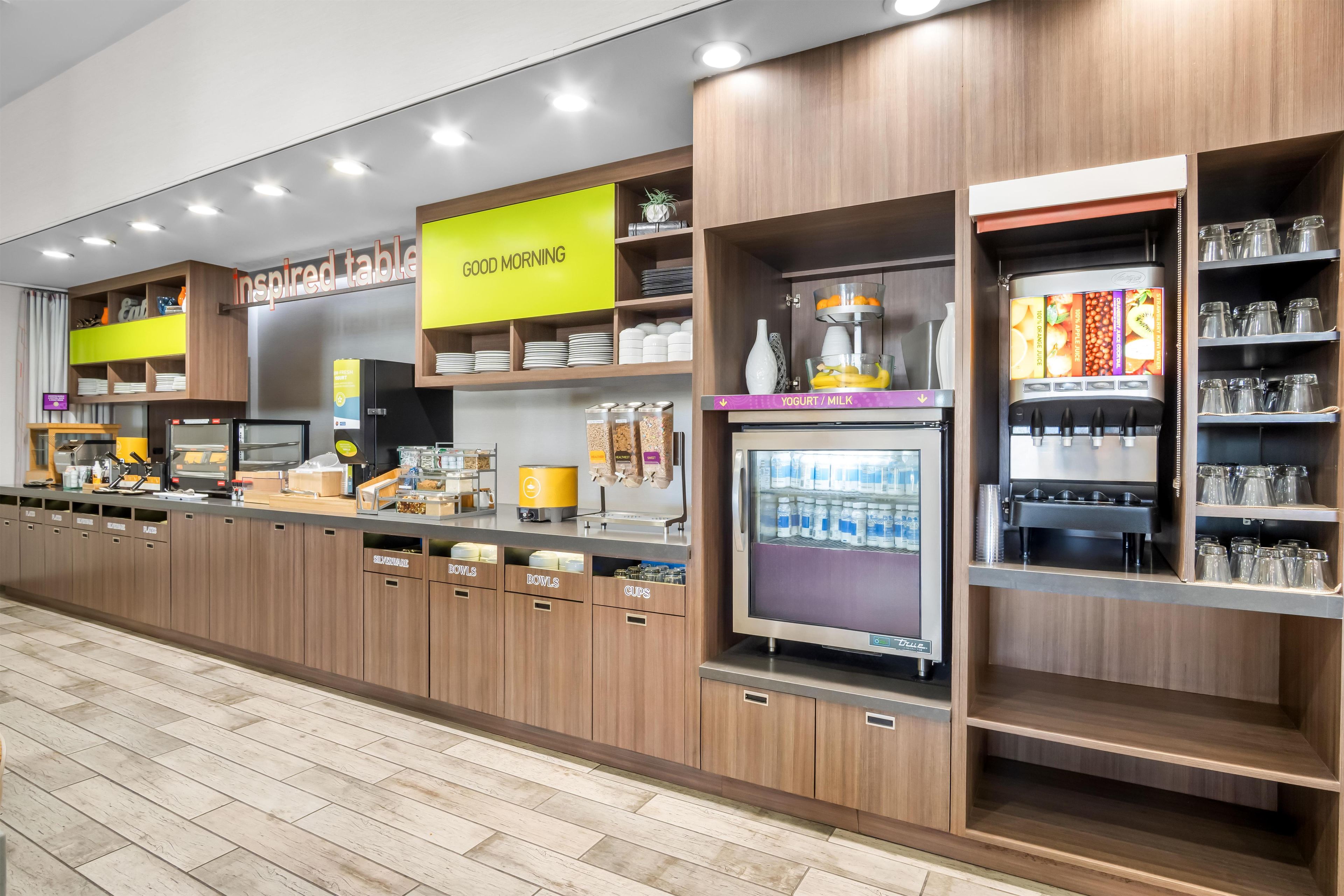 A self-service beverage station with dispensers for yogurt, milk, and juice, and a coffee machine.