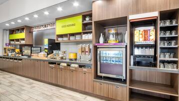A self-service beverage station with dispensers for yogurt, milk, and juice, and a coffee machine.