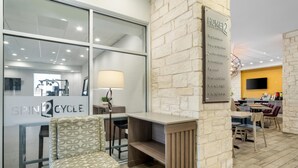 A hotel lobby with a reception desk, seating area, and a wall-mounted sign. - Home2 Suites by Hilton Fort Worth Northlake (Roanoke)