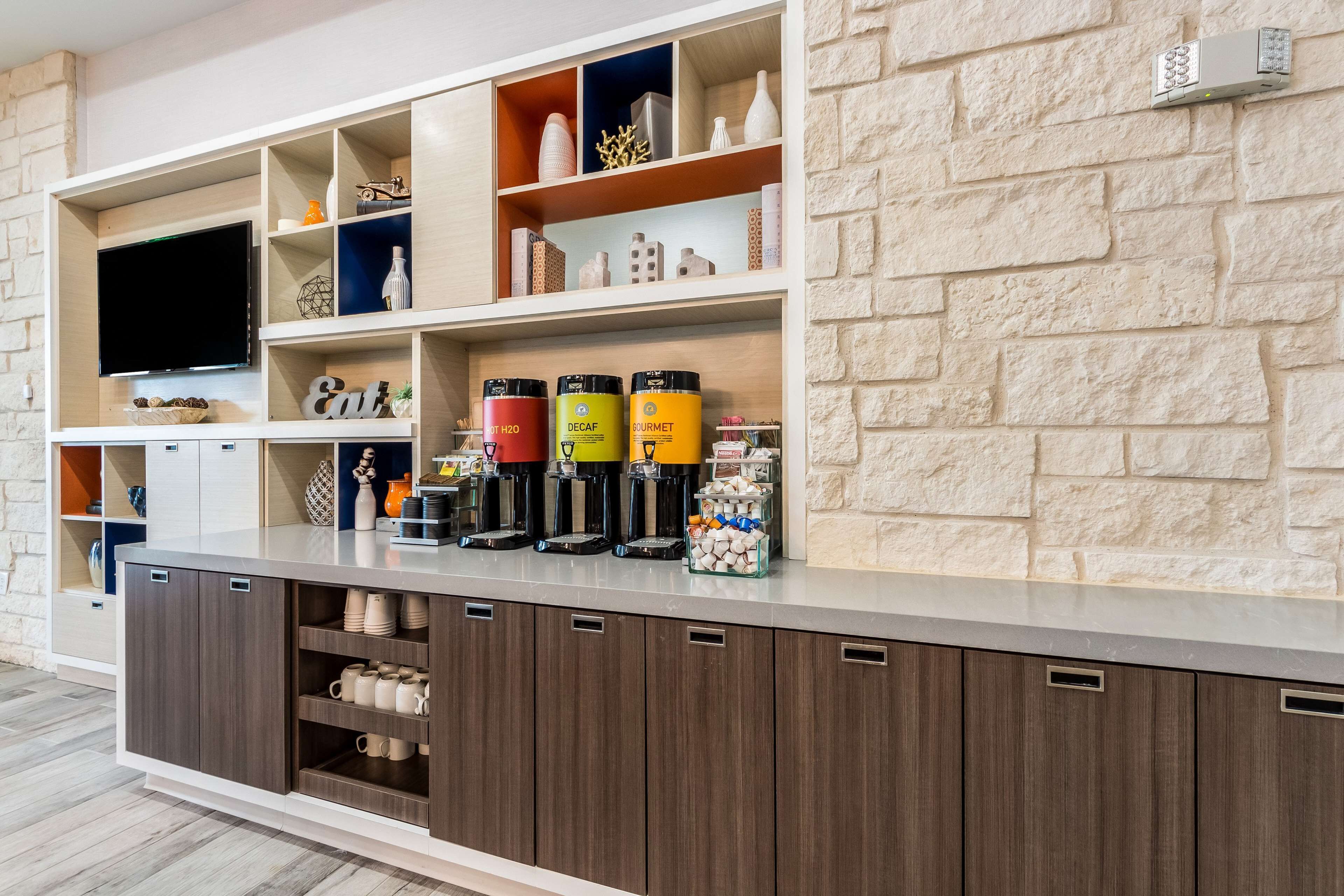 A modern kitchen with built-in appliances, a flat-screen TV, and a variety of storage cabinets.