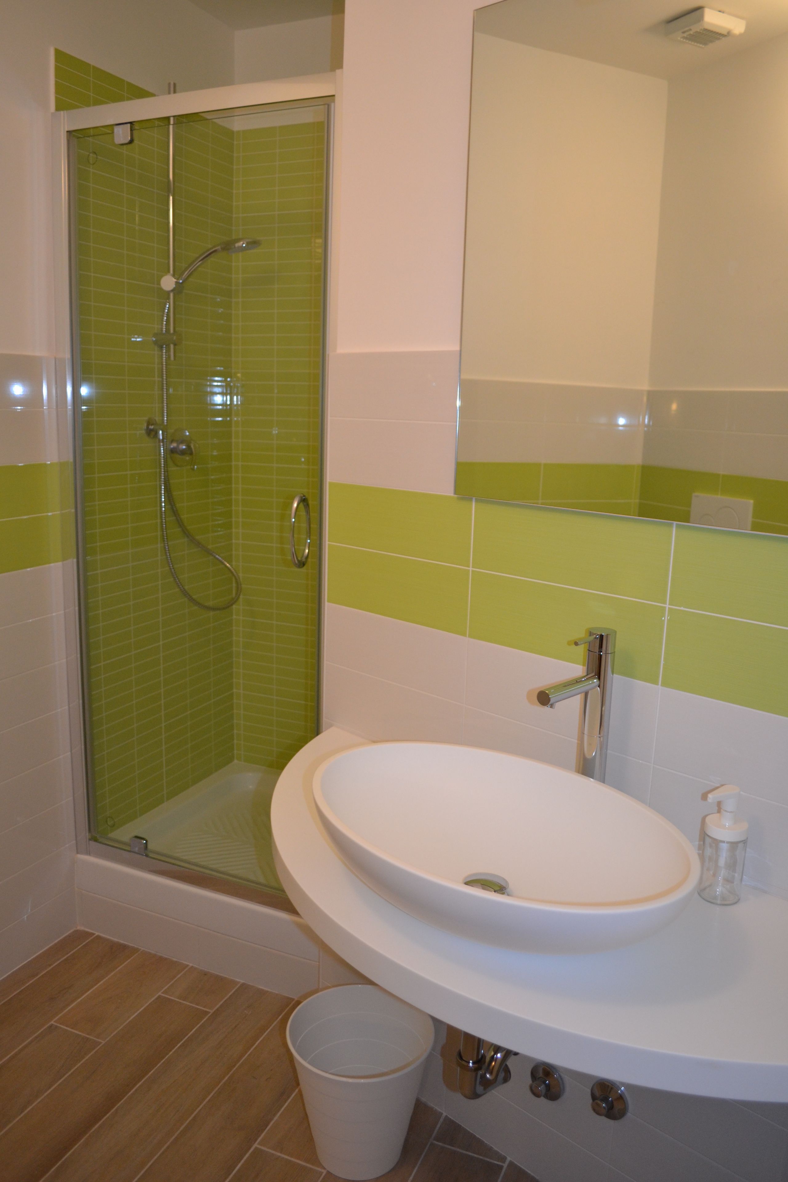 Un baño con ducha de vidrio, lavamanos blanco y espejo.