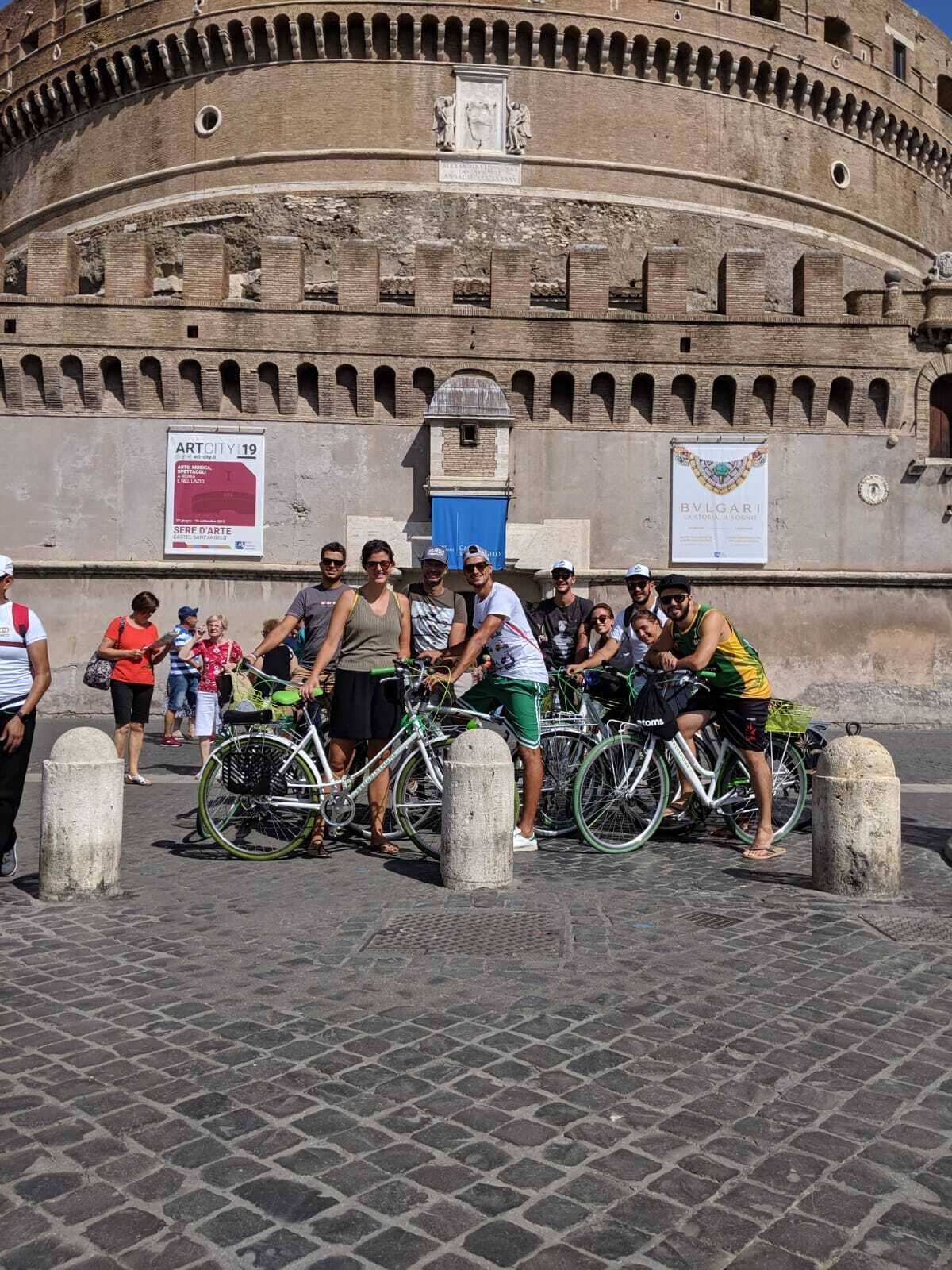 A group of people standing in front of a historic stone wall with a circular structure behind them.