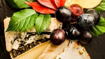 A cheese board with various cheeses, grapes, and leaves.