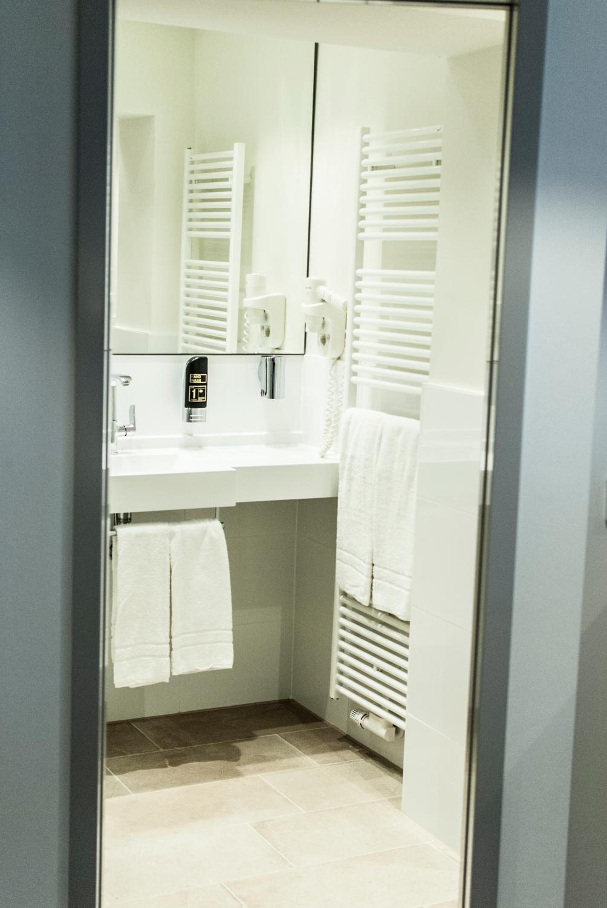 Een moderne badkamer met een wit wastafel, spiegel, handdoekhouder en een handdoek.