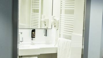 Een moderne badkamer met een wit wastafel, spiegel, handdoekhouder en een handdoek.