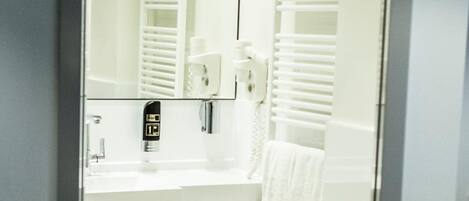 Ein modernes Badezimmer mit Waschbecken, Spiegel, Handtuchhalter und einem Handtuch.