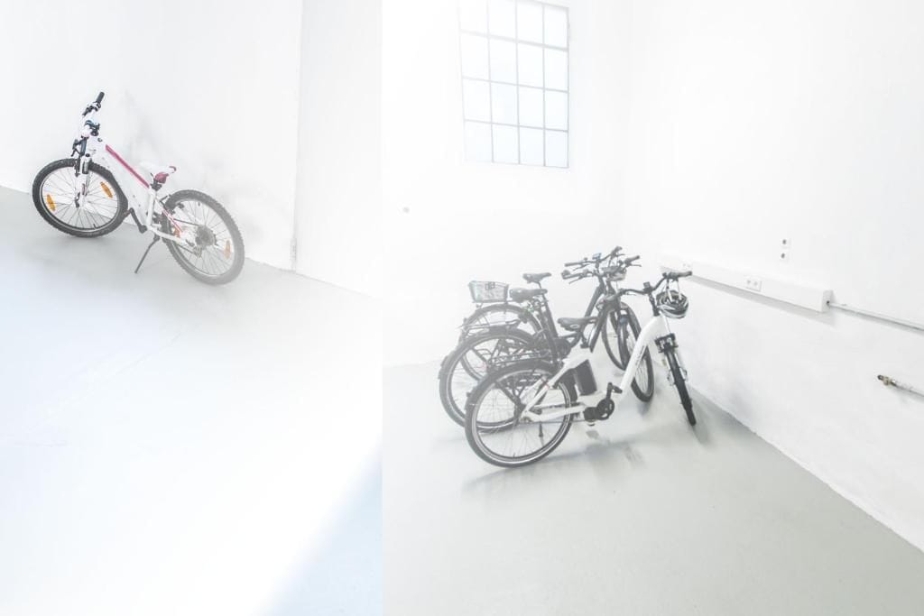 A white room with two bicycles leaning against the wall.