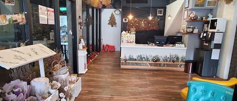 A cozy interior with a wooden floor, a reception desk, and a seating area with a teal sofa.