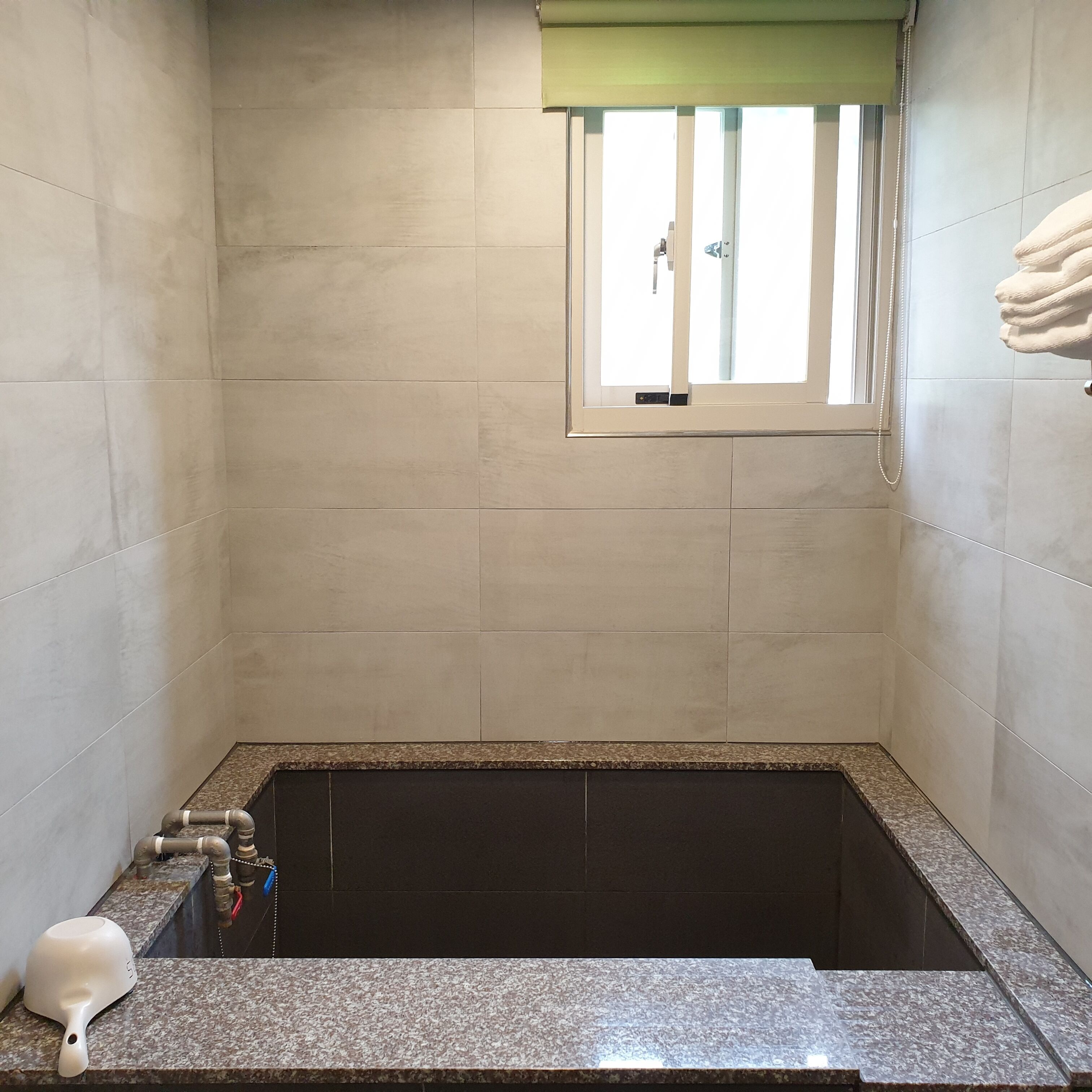 A bathroom with a bathtub, a window, and a towel rack.