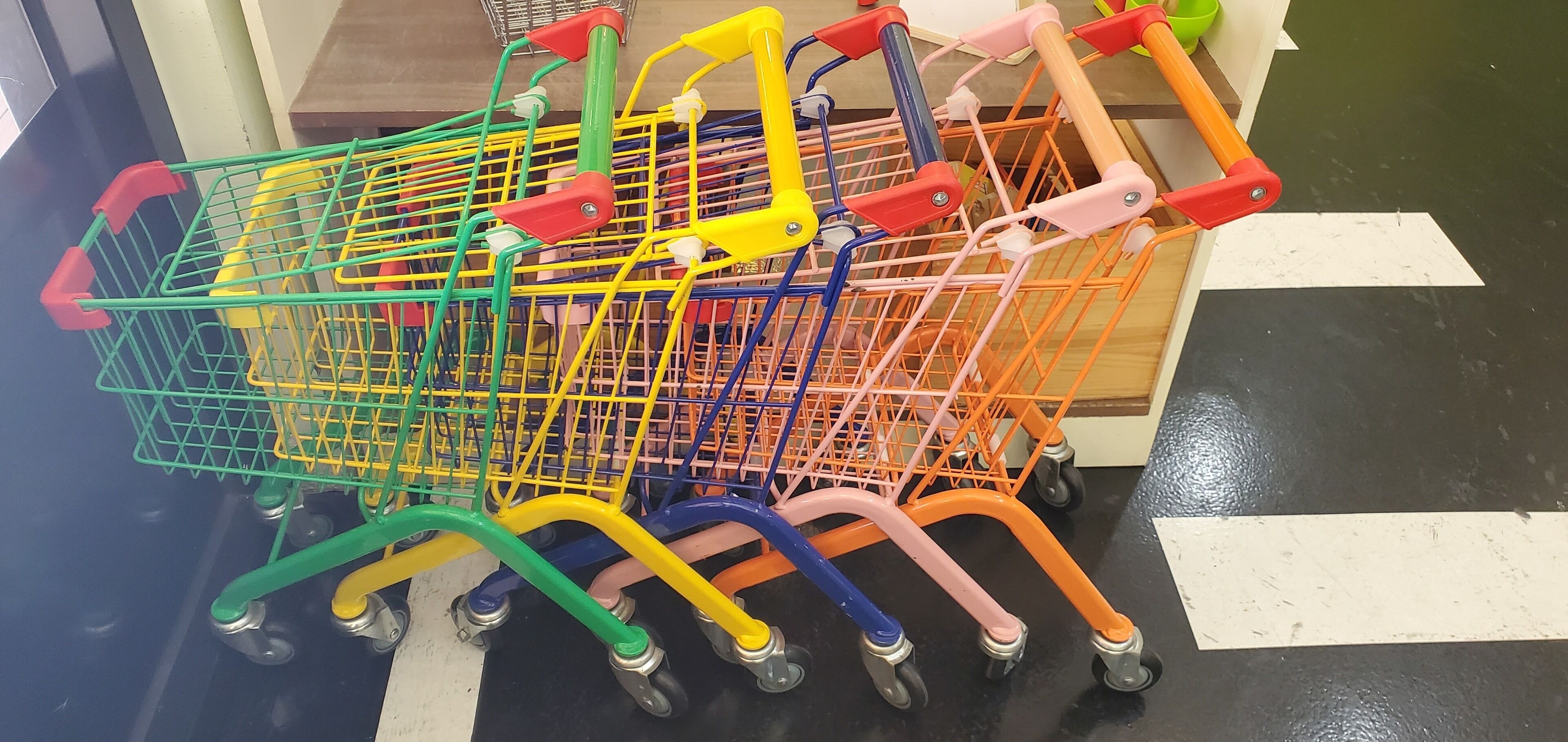 Una fila de carritos de compra coloridos en un pasillo de tienda.