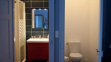 A bathroom with a red vanity, a white toilet, and a mirror above the sink.