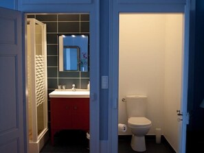 Un baño con tocador rojo, inodoro blanco y espejo sobre el lavabo.