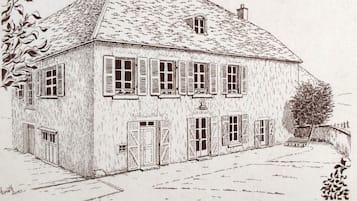 A two-story building with a steeply pitched roof, multiple windows with shutters, and a central entrance with a door.