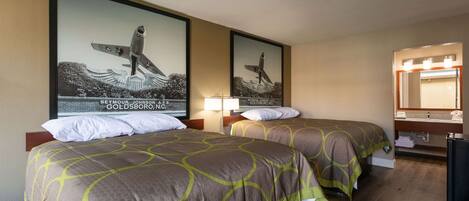 A hotel room with two beds, a large mirror, and a framed picture of a surfer on a wave.