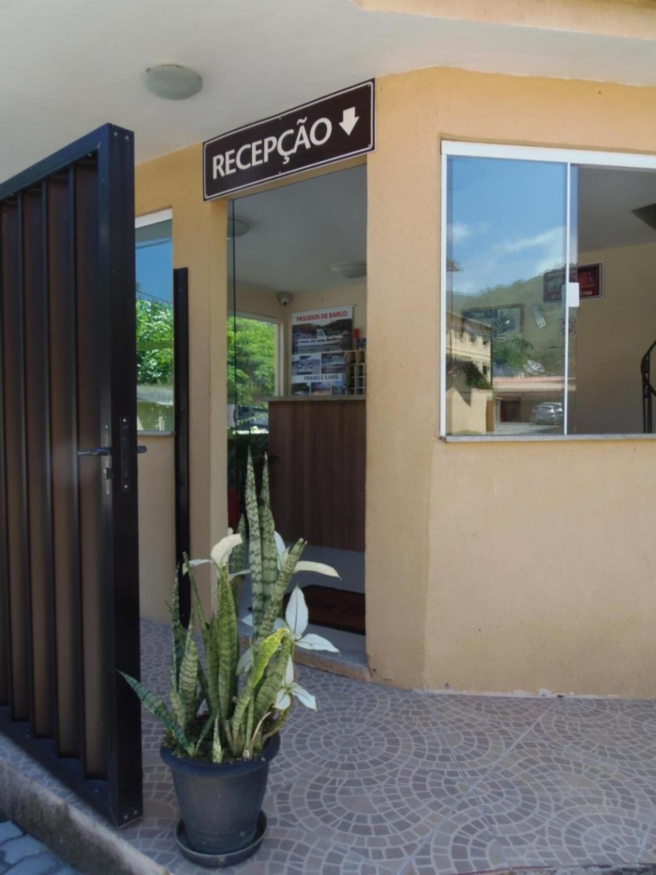 A reception area with a sign indicating the entrance, a potted plant, and a glass door leading inside.