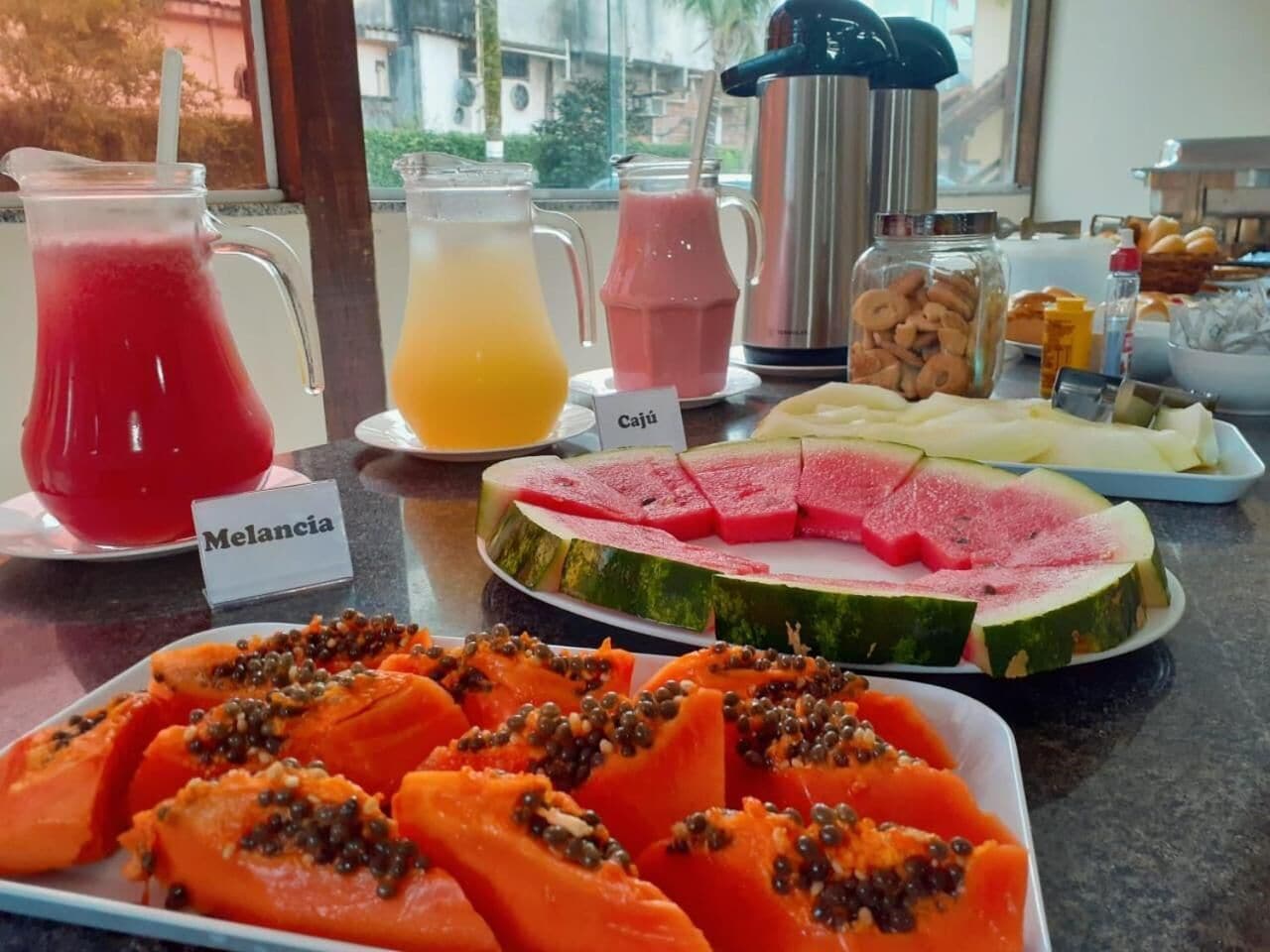 Monipuolinen aamiaisbuffet, jossa on tarjolla erilaisia hedelmiä, mehuja ja leivonnaisia.