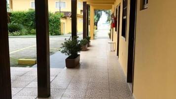 A corridor with tiled flooring, potted plants, and a row of doors on one side.