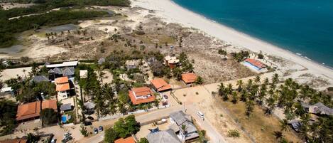 An aerial view of a coastal area with a beach, houses, and vegetation.
