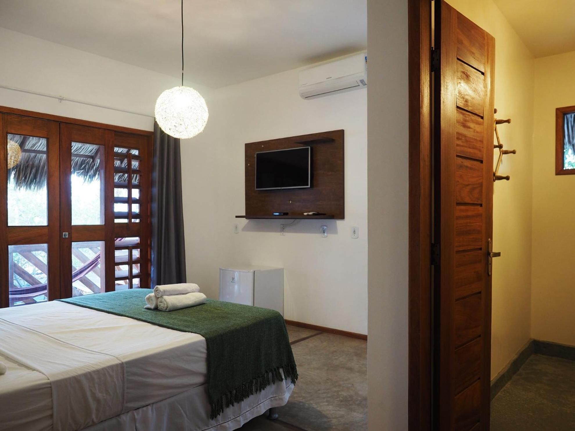 Een hotelkamer met een bed, een aan de muur bevestigde televisie, een airconditioning en een houten kledingkast.