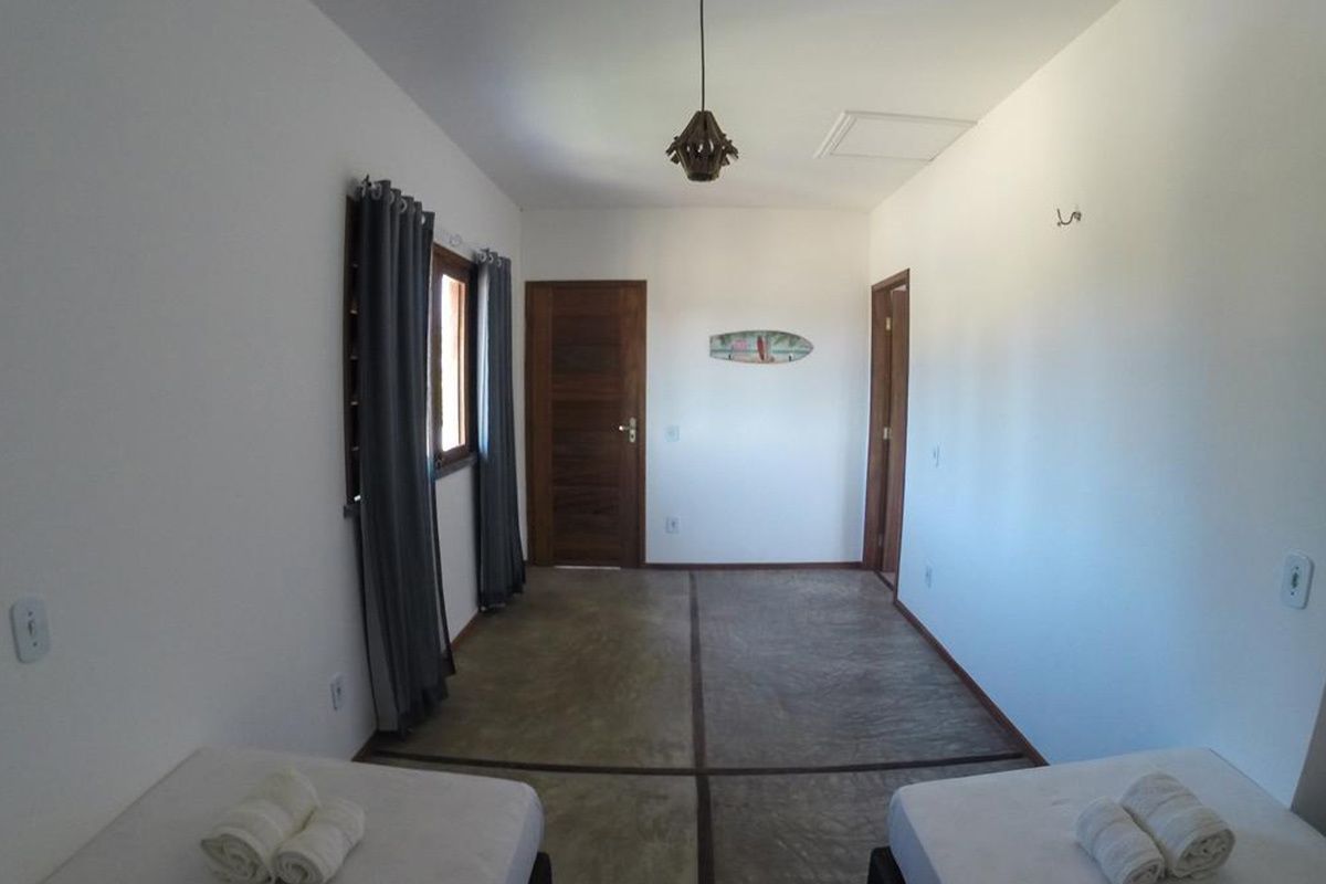 Habitación de hotel con cama, ventana con cortinas, una puerta y una lámpara fijada a la pared.